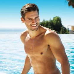 Lächelnder Mann im Pool blickt zur Seite, wodurch man das gelungene Ergebnis der Nasenunterspritzung mit Hyaluronsäure erkennen kann.